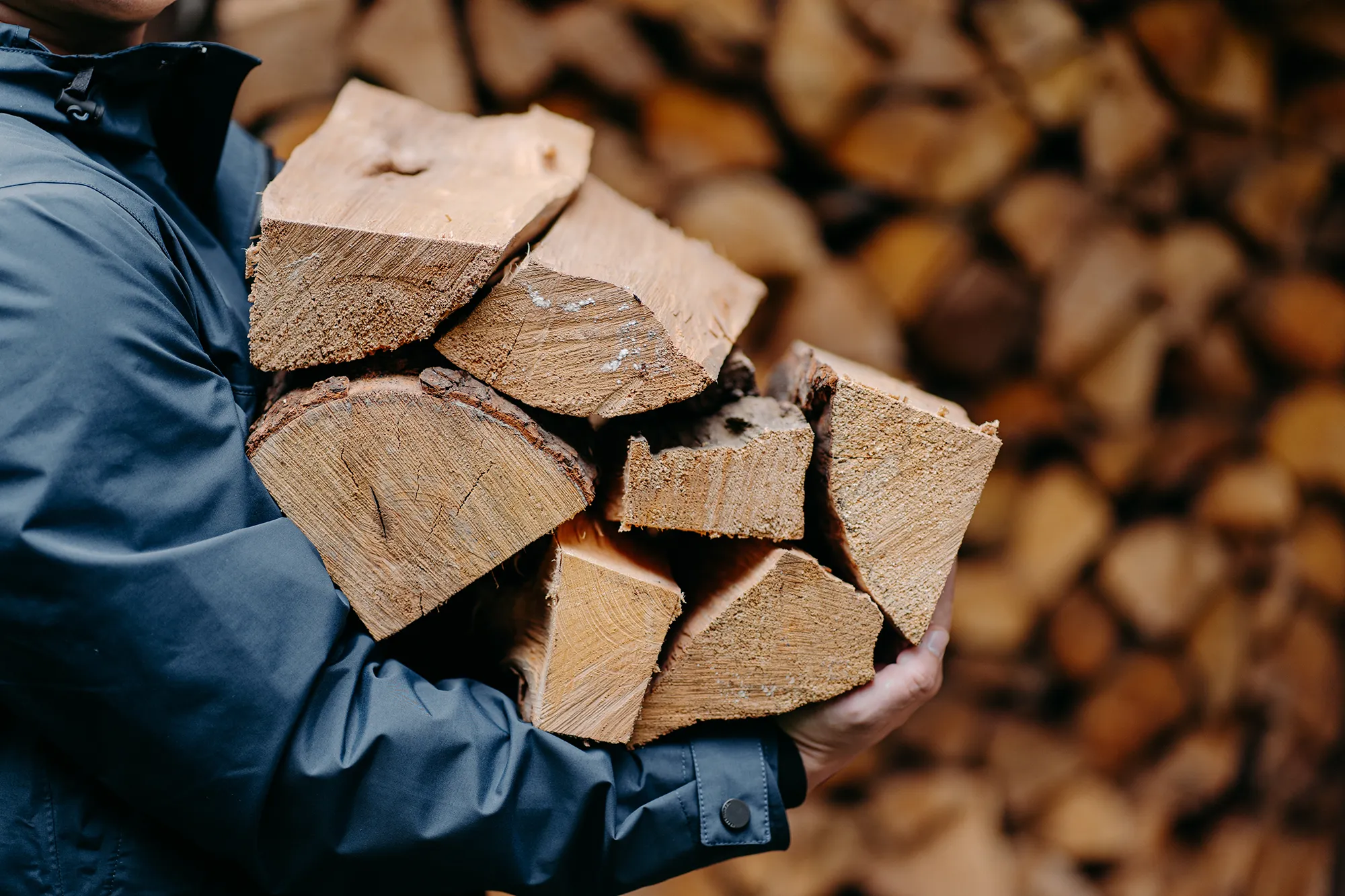 Ein Mann präsentiert einen Stapel Holz, der in seinen Händen ruht.